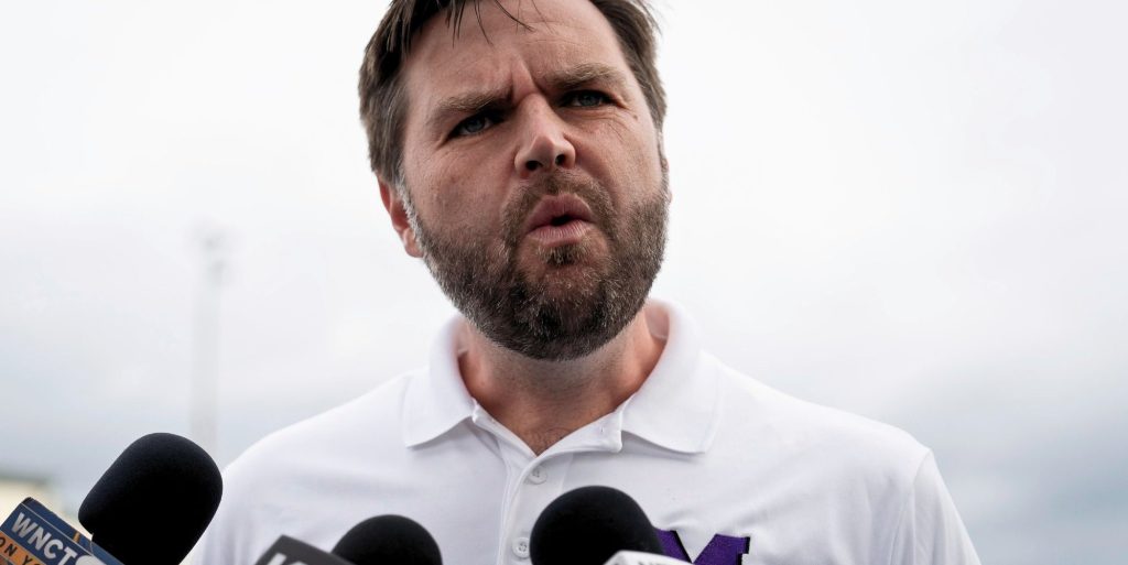 JD Vance, pictured speaking into a set of microphones.