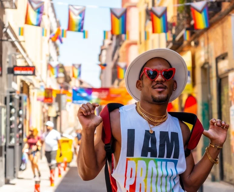 Un hombre negro gay en la fiesta del orgullo visitando la decoración de la ciudad, bandera LGBT
