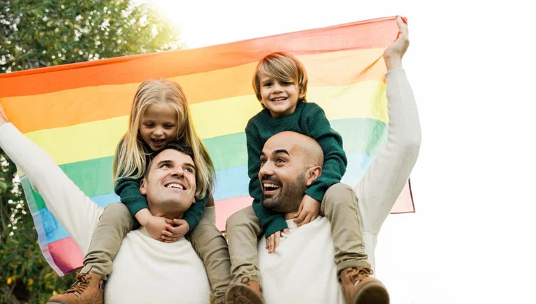 Familia Lgbt: Padres homosexuales y niños celebrando con la bandera del arco iris al aire libre en Park City - Concepto de padres de diversidad - Enfoque en papá