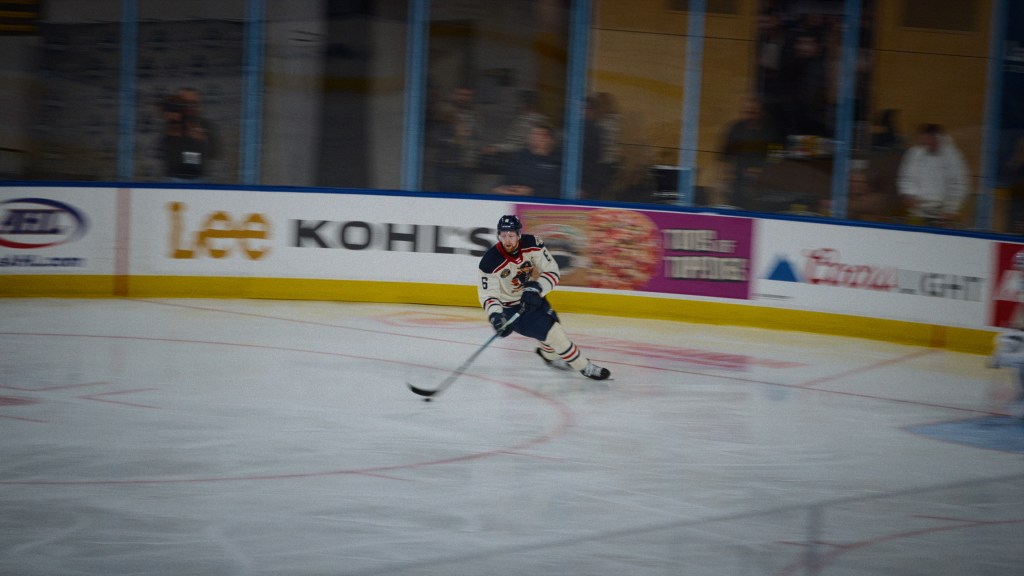 El jugador de hockey todavía: Luke Prokop patinando sobre una pista borrosa