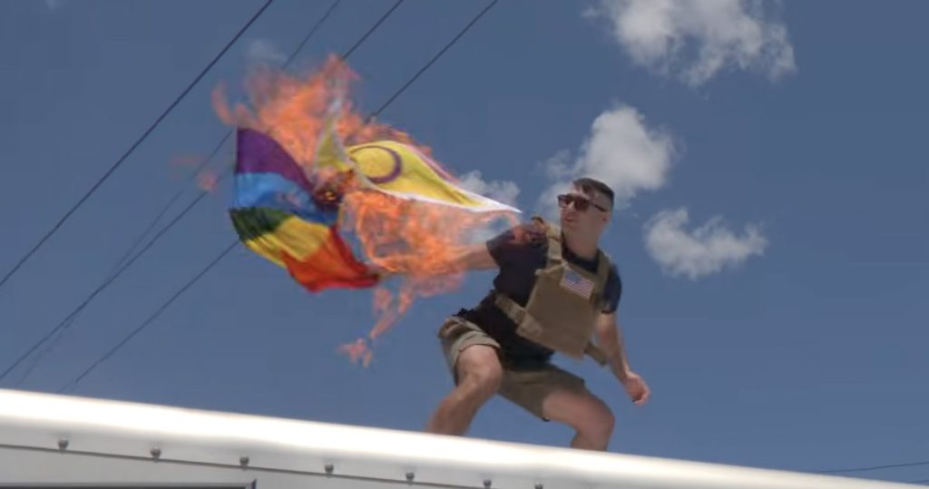 El candidato republicano lucha por quemar la bandera del arco iris en la parte superior de un camión U-Haul mientras les grita a 2 personas