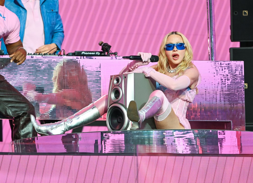 Madonna sentada con un altavoz entre las piernas en un concierto