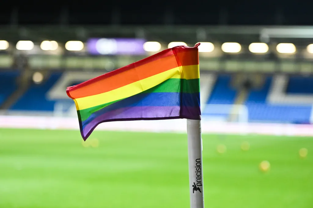 Bandera arcoíris plantada en un campo de fútbol.